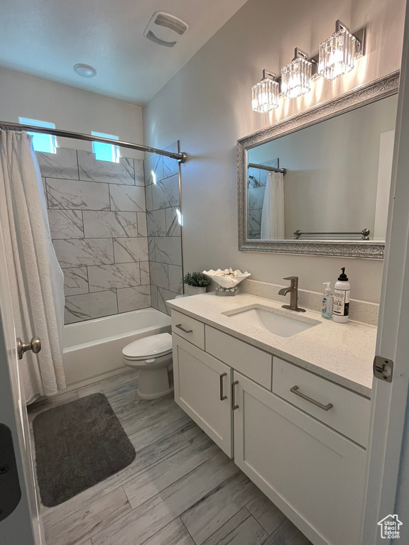 Full bathroom featuring large vanity, shower / tub combo, and toilet