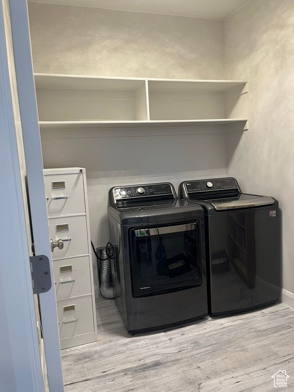 Clothes washing area with light hardwood / wood-style flooring and washing machine and dryer