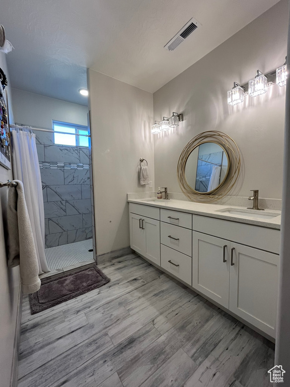 Bathroom with dual vanity, curtained shower, and wood-type flooring