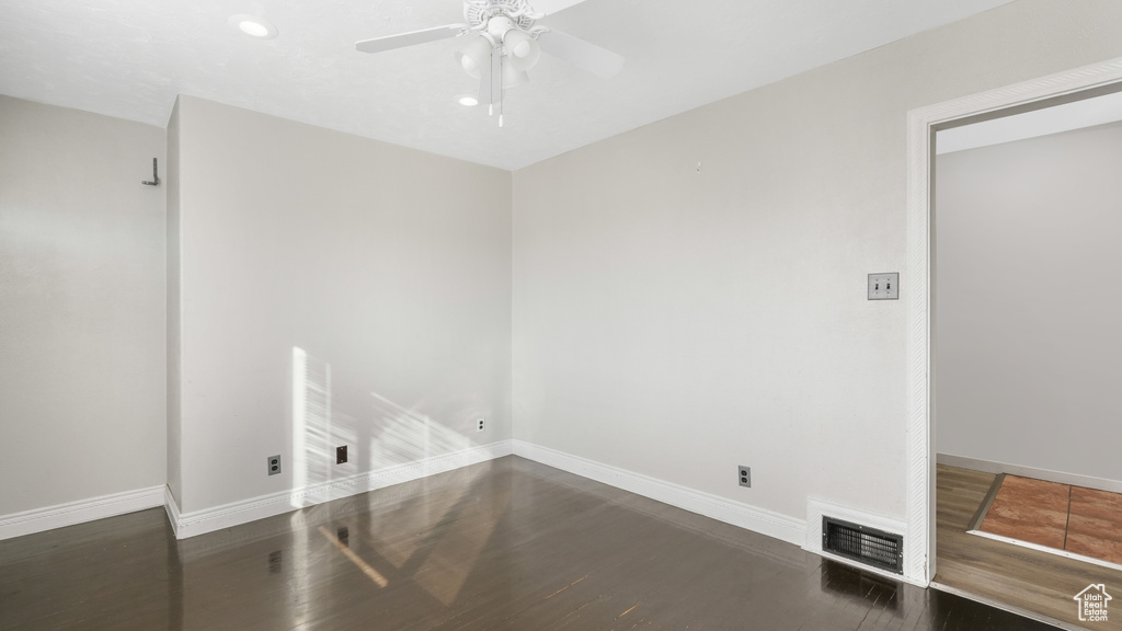Unfurnished room featuring dark wood-type flooring and ceiling fan
