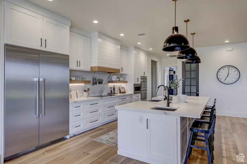 Kitchen with white cabinets, stainless steel appliances, and light wood-type flooring