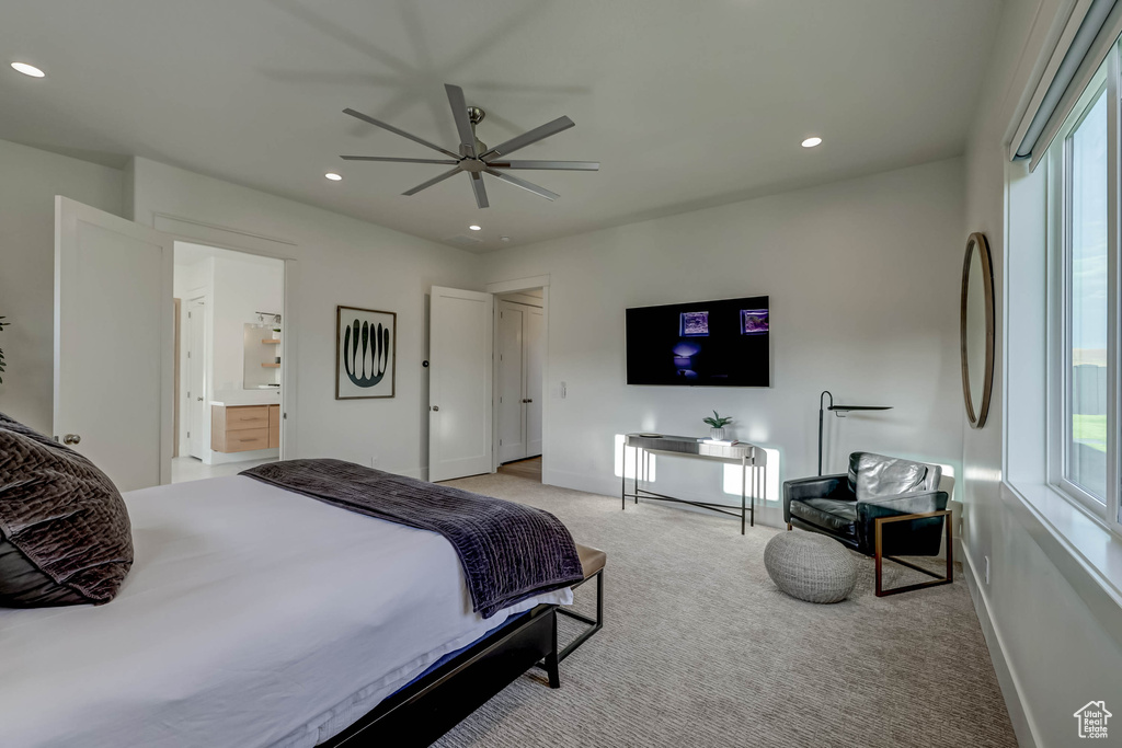 Carpeted bedroom featuring multiple windows, ensuite bathroom, and ceiling fan
