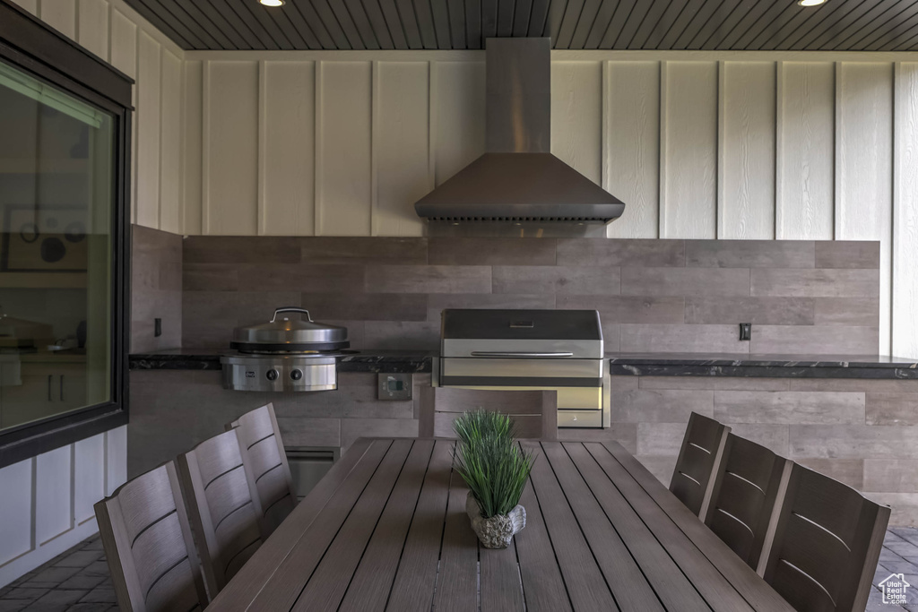 Exterior space featuring cream cabinets and wall chimney range hood