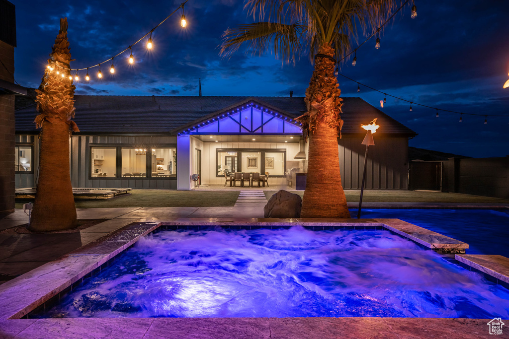 Pool at twilight with an in ground hot tub and a patio