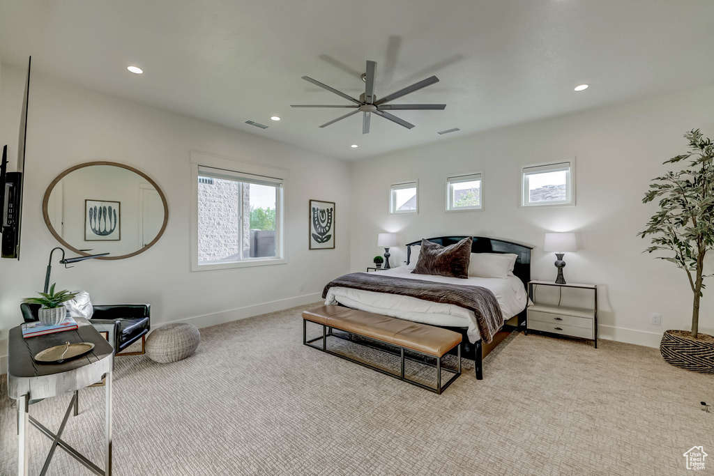 Bedroom with multiple windows, ceiling fan, and light colored carpet