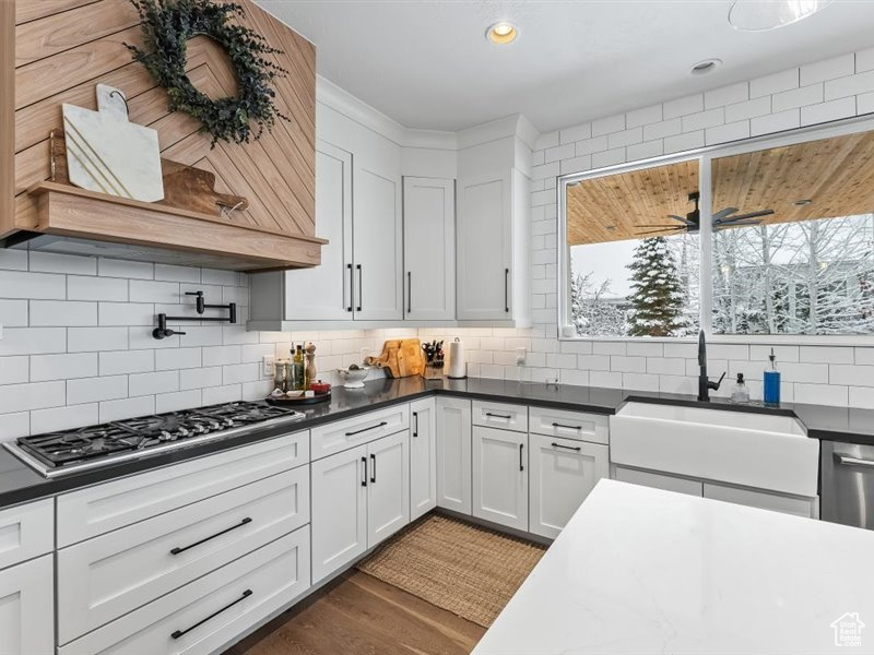 Kitchen with dark hardwood / wood-style flooring, ceiling fan, backsplash, and white cabinetry