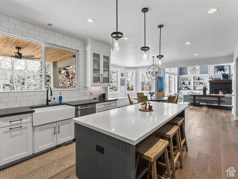 Kitchen featuring pendant lighting, ceiling fan with notable chandelier, a kitchen island, hardwood / wood-style flooring, and tasteful backsplash