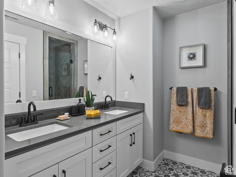 Bathroom with an enclosed shower, tile flooring, double sink, and vanity with extensive cabinet space