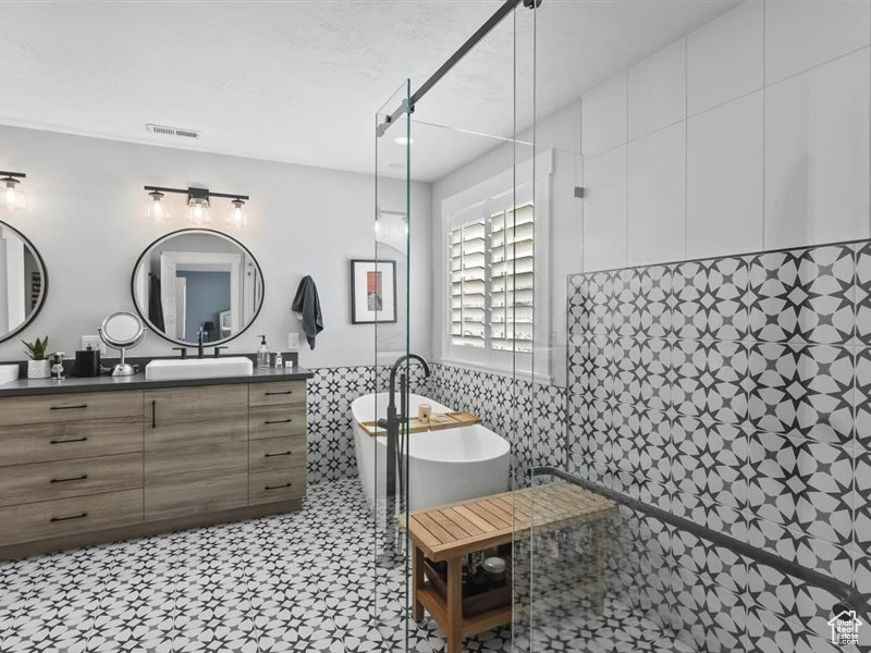 Bathroom with vanity, a bathing tub, tile floors, and tile walls