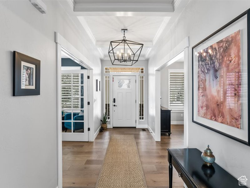 Foyer entrance with a chandelier, dark hardwood / wood-style flooring, and crown molding