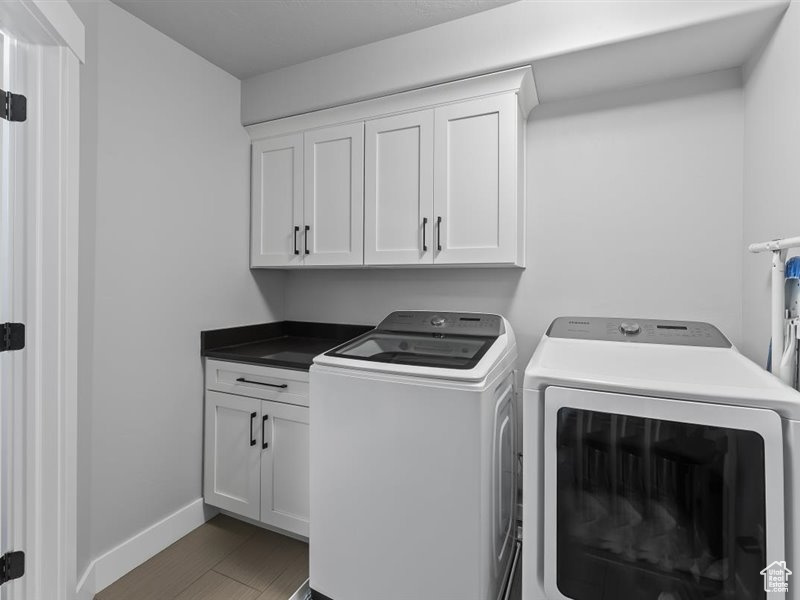 Laundry room with washer and clothes dryer and cabinets