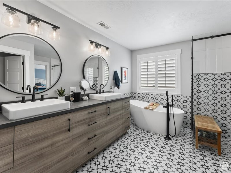 Bathroom featuring dual vanity, tile walls, a bathing tub, and tile flooring