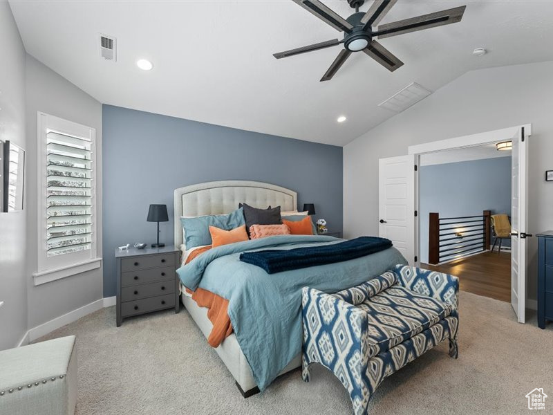 Bedroom featuring ceiling fan, light colored carpet, and lofted ceiling