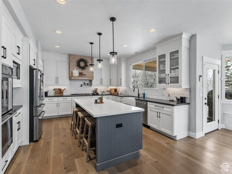Kitchen featuring custom exhaust hood, dark wood-type flooring, a kitchen island, and stainless steel appliances