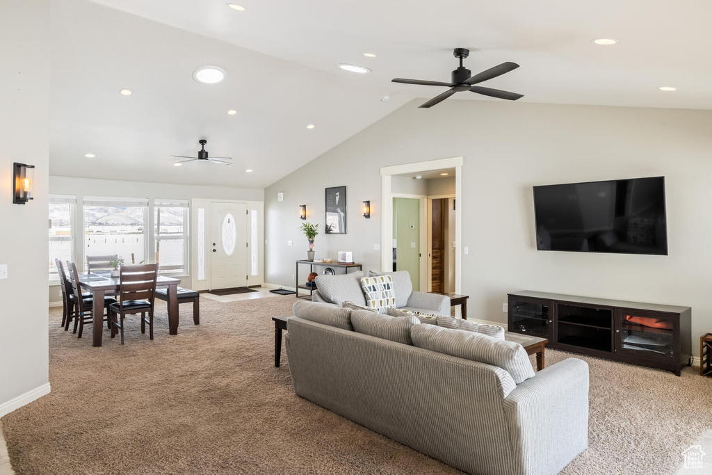 Living room with high vaulted ceiling, ceiling fan, and light carpet