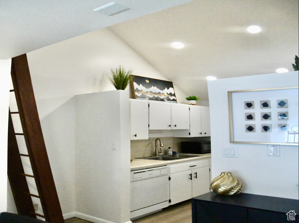 Kitchen featuring light hardwood / wood-style floors, white dishwasher, white cabinets, tasteful backsplash, and sink