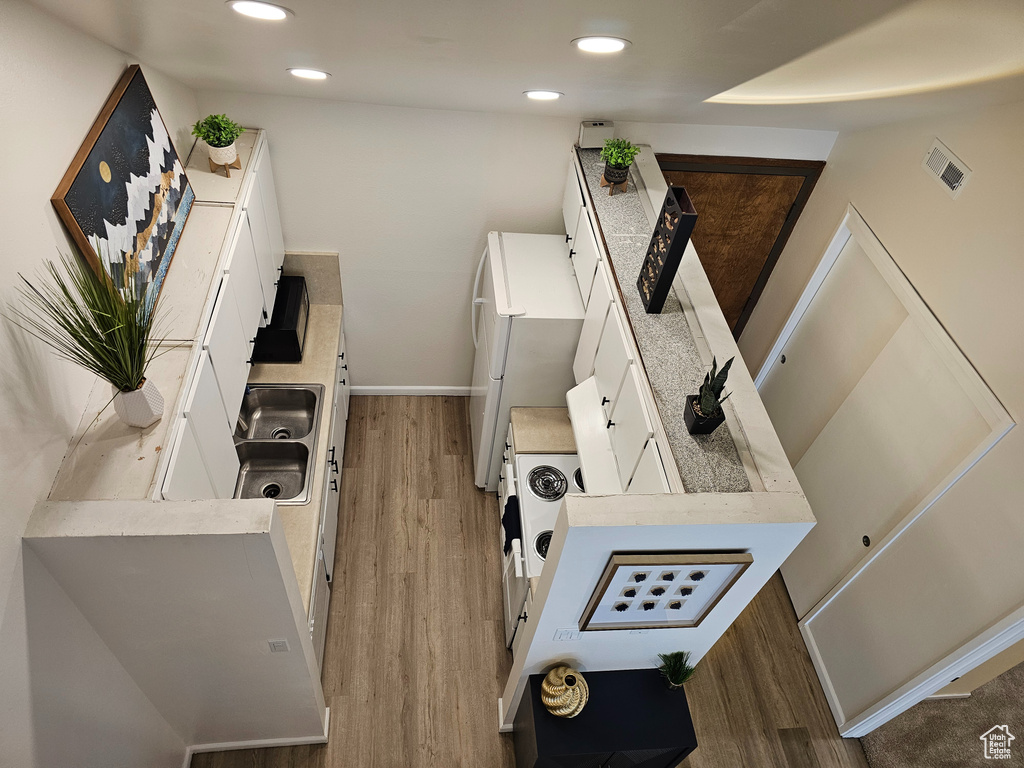 Kitchen with hardwood / wood-style flooring, white refrigerator, and white cabinetry