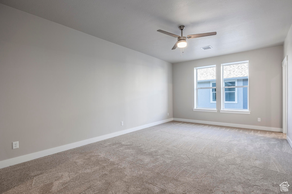 Empty room with ceiling fan and light colored carpet