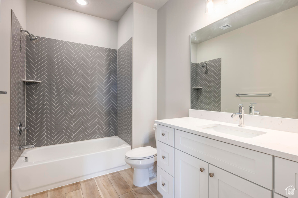 Full bathroom featuring oversized vanity, toilet, hardwood / wood-style flooring, and tiled shower / bath