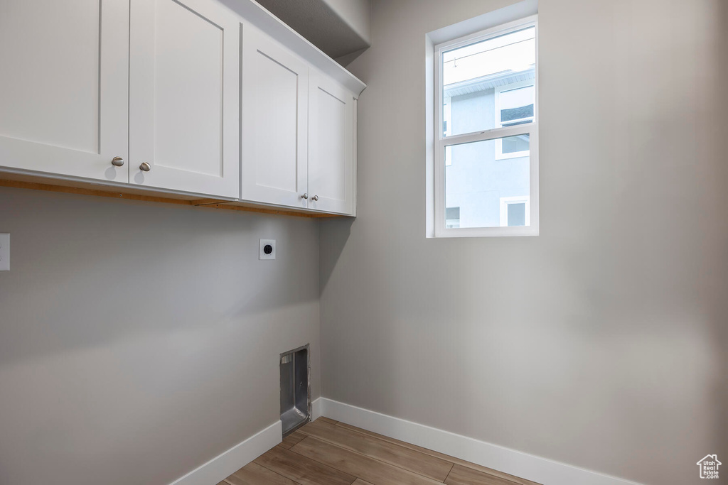 Laundry room with cabinets, light hardwood / wood-style flooring, and electric dryer hookup