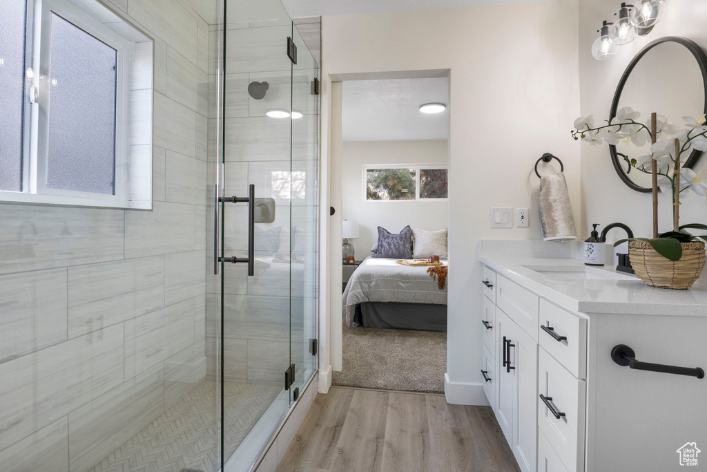Bathroom featuring wood-type flooring, vanity, and walk in shower