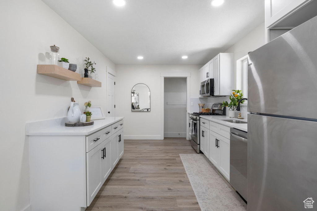 Kitchen featuring white cabinets, light hardwood / wood-style floors, and appliances with stainless steel finishes