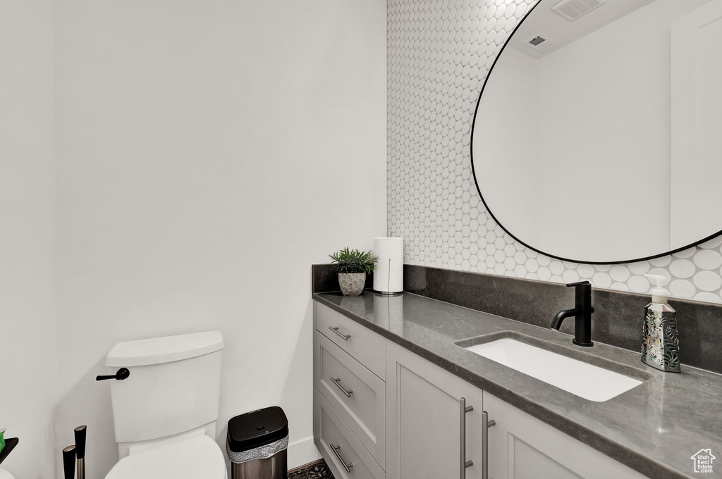 Bathroom with vanity, toilet, and backsplash