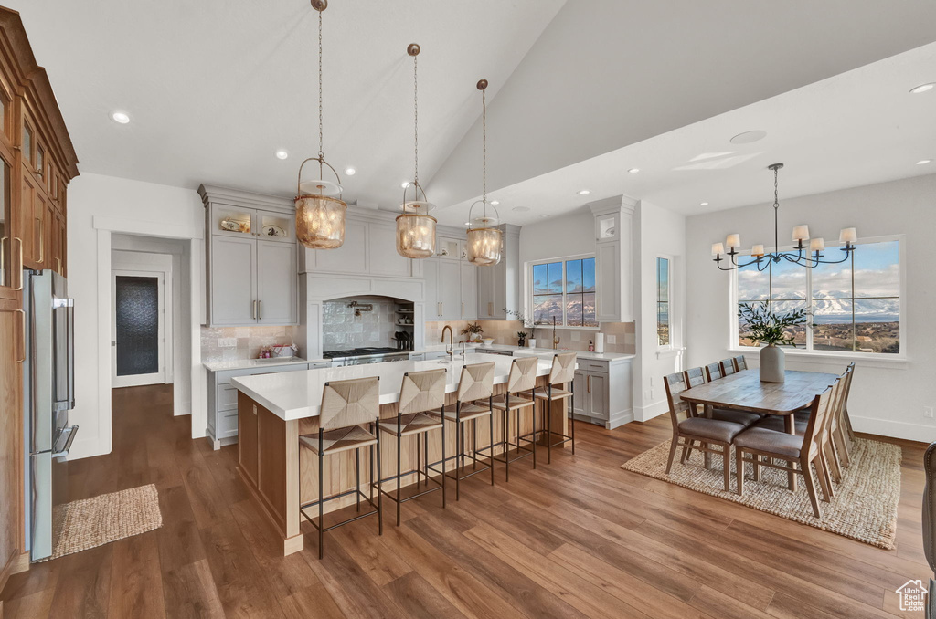 Kitchen featuring a kitchen island with sink, an inviting chandelier, dark hardwood / wood-style flooring, pendant lighting, and a healthy amount of sunlight