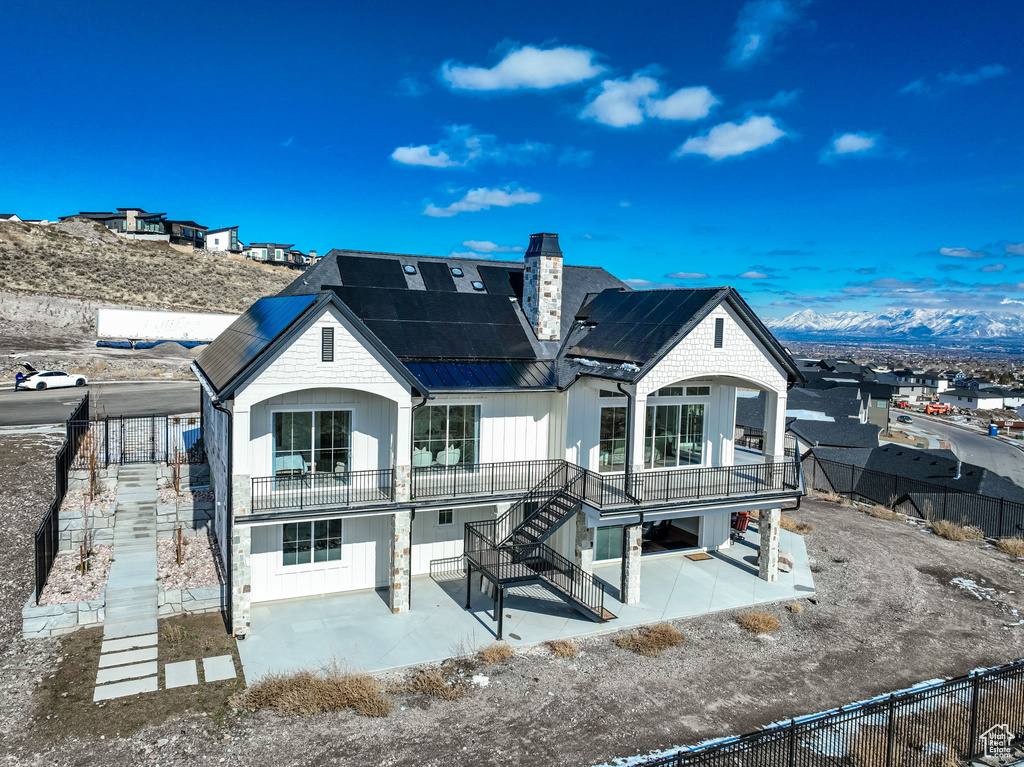 Rear view of property featuring solar panels, a mountain view, and a balcony