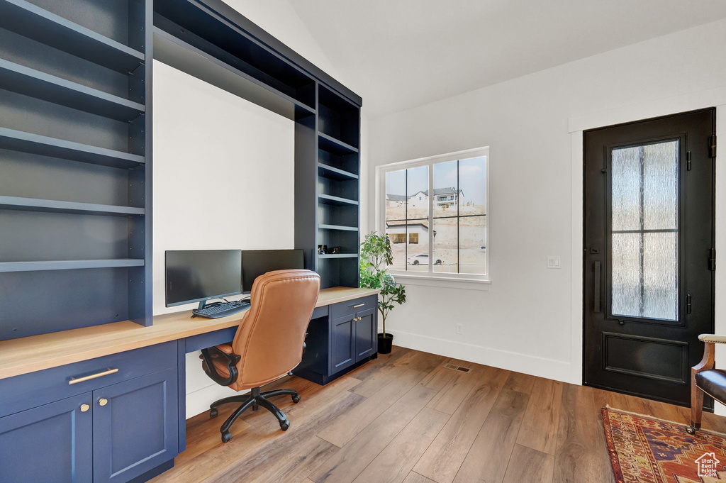 Office space with plenty of natural light, built in shelves, built in desk, and dark wood-type flooring