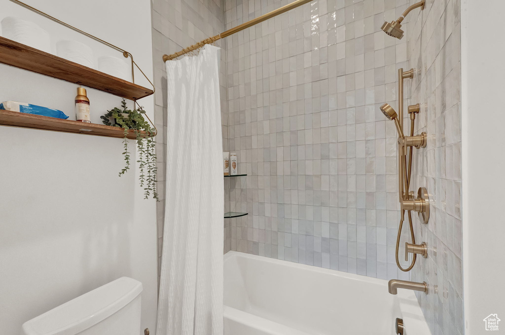Bathroom with toilet and shower / bath combo with shower curtain