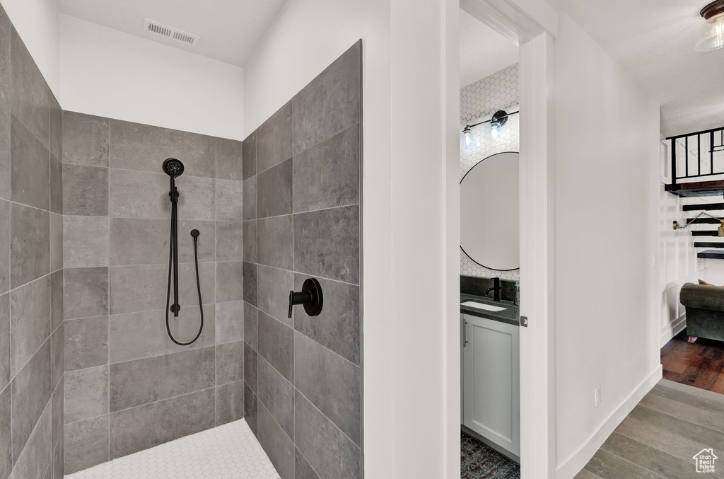 Bathroom featuring vanity, a tile shower, and wood-type flooring