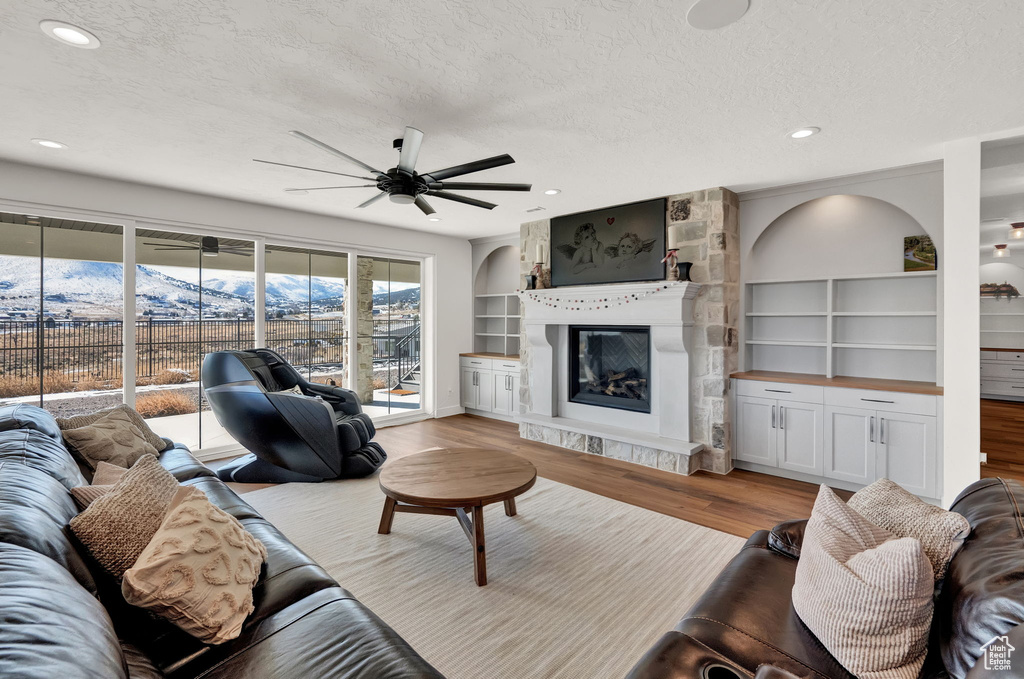 Living room featuring light hardwood / wood-style floors, ceiling fan, a textured ceiling, and built in features