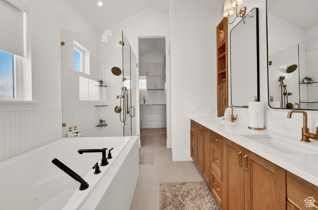 Bathroom with a wealth of natural light, double vanity, tile floors, and lofted ceiling