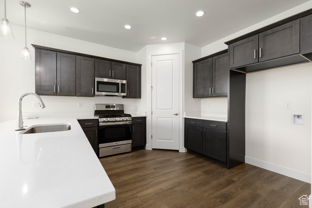 Kitchen with sink, decorative light fixtures, appliances with stainless steel finishes, and dark hardwood / wood-style flooring