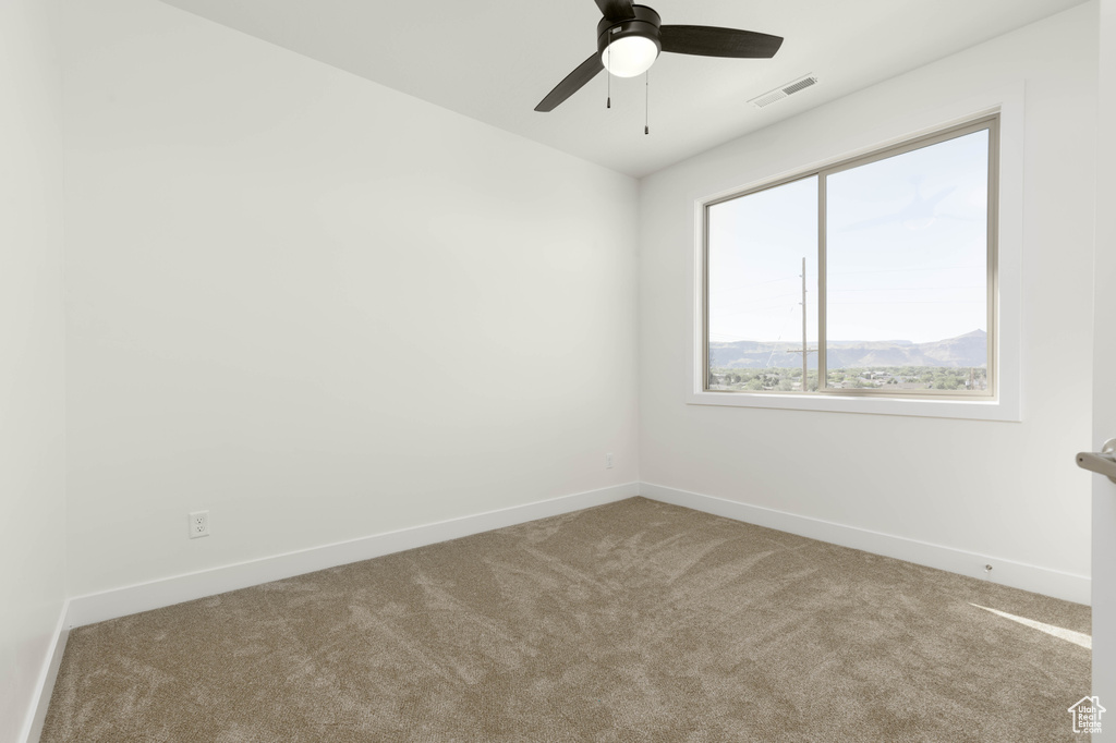 Carpeted empty room featuring ceiling fan