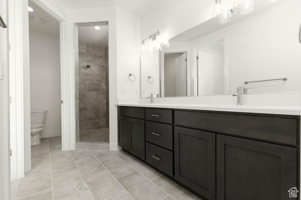 Bathroom with vanity, toilet, a tile shower, and tile patterned floors