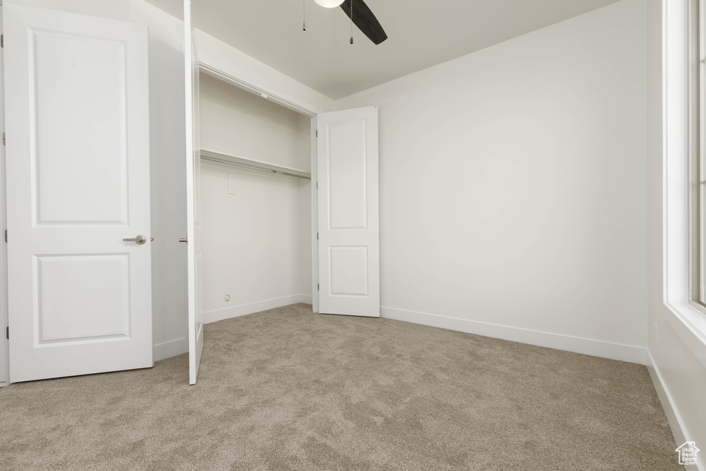 Unfurnished bedroom with light colored carpet, ceiling fan, and a closet