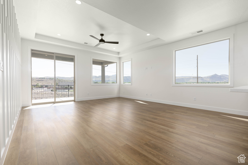 Empty room featuring a tray ceiling, ceiling fan, and hardwood / wood-style flooring