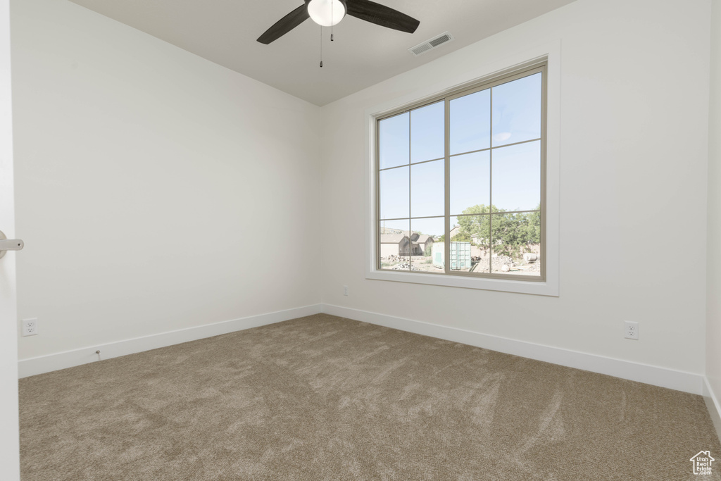 Carpeted spare room featuring ceiling fan