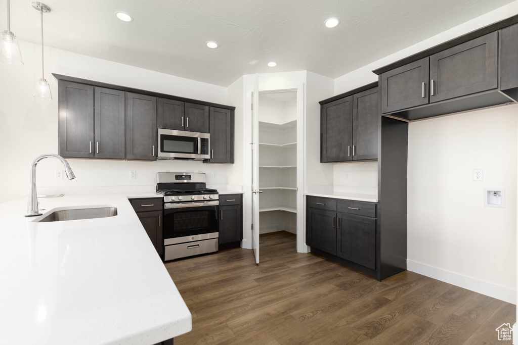 Kitchen featuring dark wood-type flooring, appliances with stainless steel finishes, pendant lighting, and sink