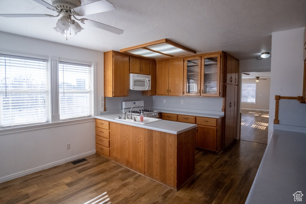 Kitchen featuring gas stove, kitchen peninsula, sink, dark hardwood / wood-style floors, and ceiling fan
