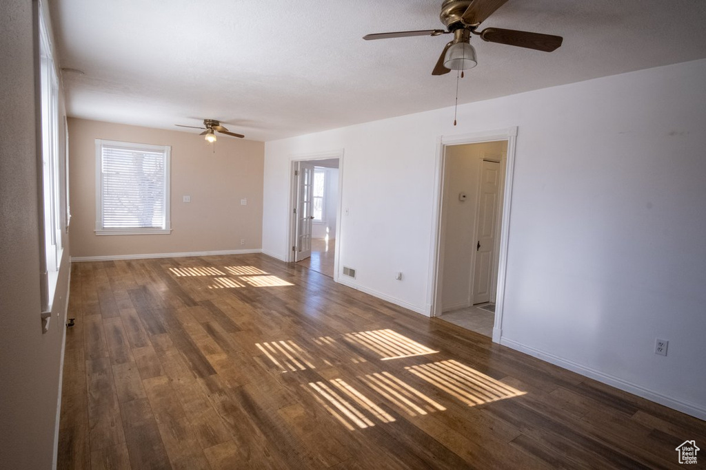 Spare room featuring a healthy amount of sunlight, dark wood-type flooring, and ceiling fan