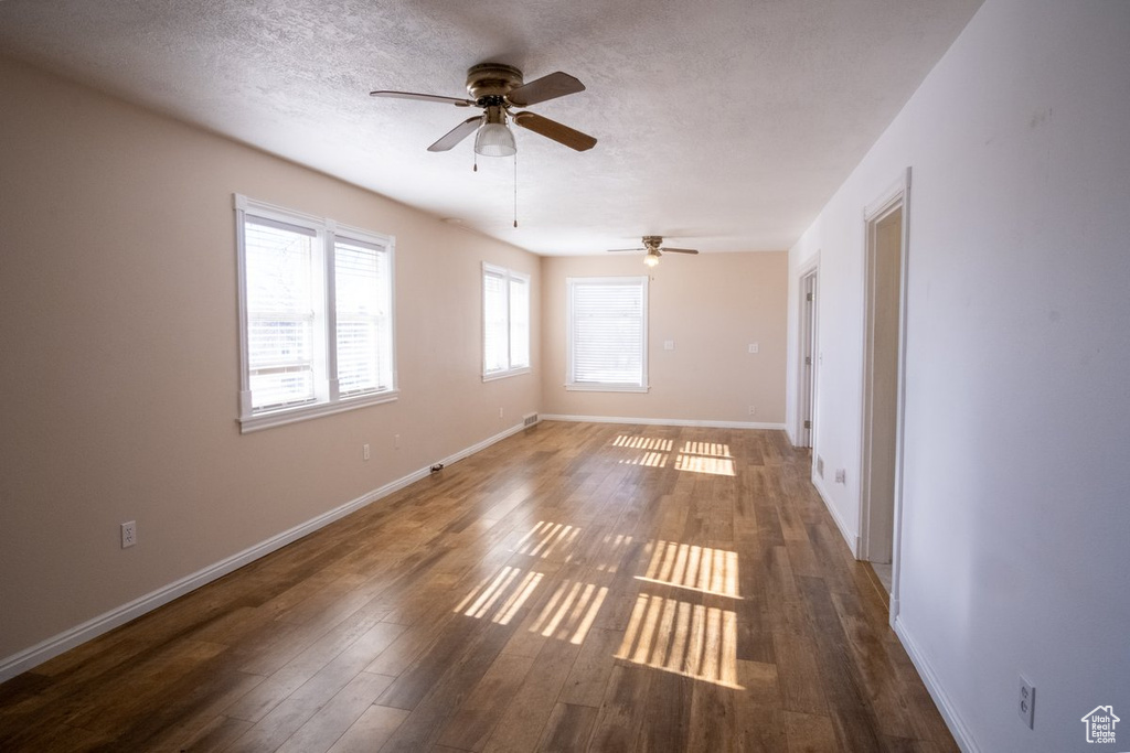 Spare room with ceiling fan, a textured ceiling, and dark wood-type flooring