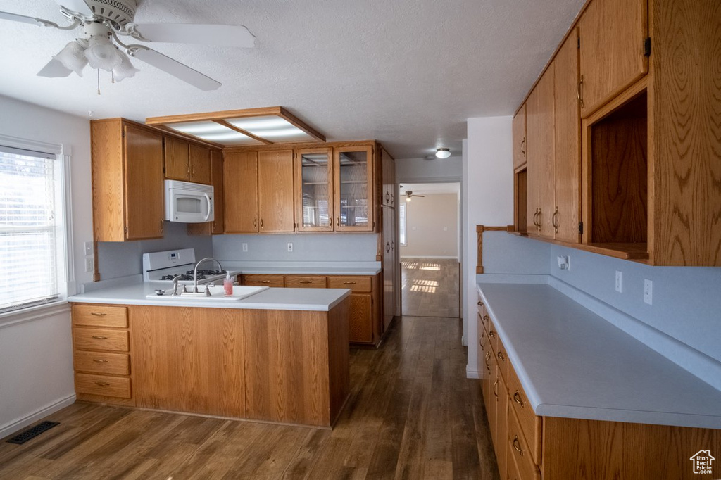 Kitchen featuring dark hardwood / wood-style floors, white appliances, ceiling fan, and kitchen peninsula