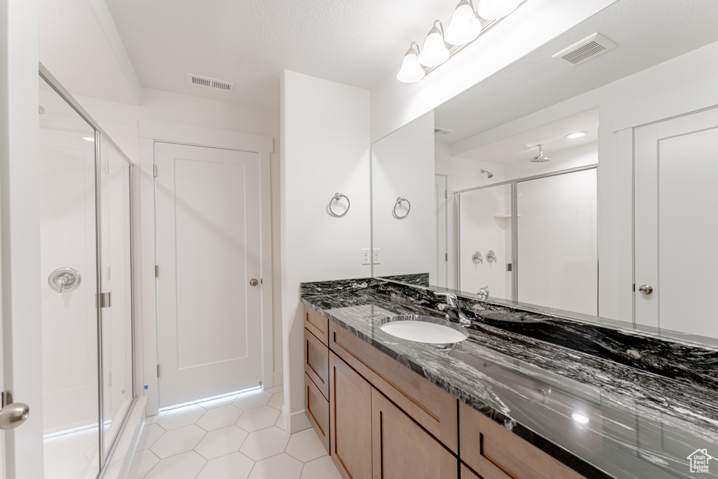 Bathroom featuring a shower with door, tile flooring, and vanity