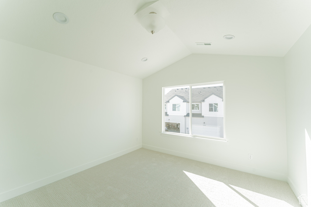 Unfurnished room with lofted ceiling and light colored carpet