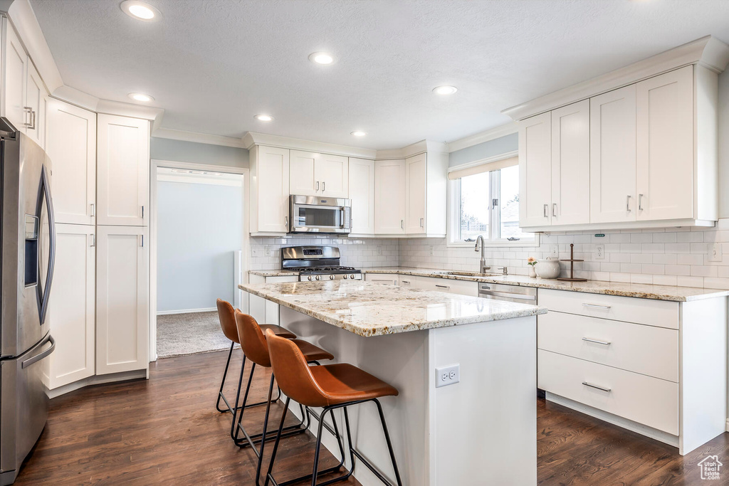 Kitchen featuring white cabinets, dark hardwood / wood-style floors, appliances with stainless steel finishes, and a kitchen island