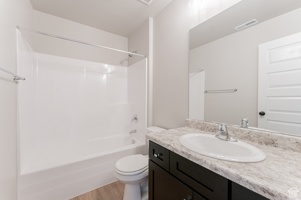 Full bathroom with oversized vanity, toilet, shower / tub combination, and hardwood / wood-style flooring