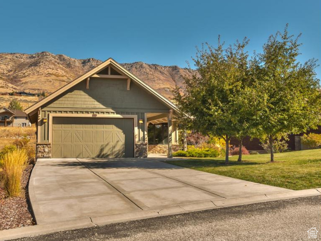 View of front of property with a front lawn, a garage, and a mountain view